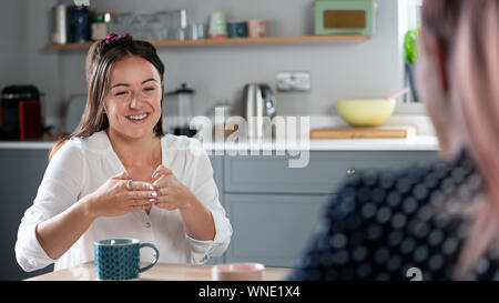Two Women Having Conversation At Home Using Sign Language Stock Photo