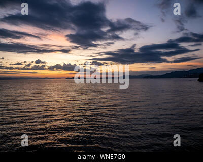 the sun sets over Omura bay in Nagasaki Prefecture, Japan as seen from the Sasebo Seaside Line. Stock Photo