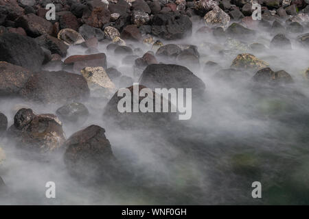 Big  volcanic coast rocks, with waves silky foam movement, long exposure photography, with sunset light, Atlantic ocean, Canary islands, Spain Stock Photo