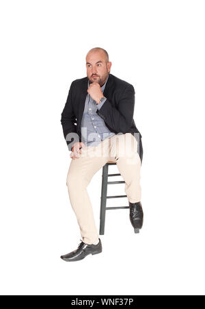 A puzzled middle age business man sitting on a chair with his hand on his chin, looking for a solution for his problem, isolated for white background Stock Photo