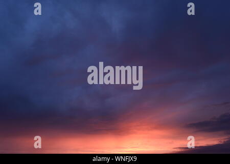Cloudy blue  sky in the bright yellow and red sunlight of sunset Stock Photo