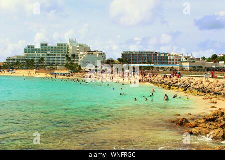 Tourists, holidaymakers & plane-spotters, relax in the sea and on the sands at Maho beach, next to Princess Juliana International Airport, St Maarten. Stock Photo