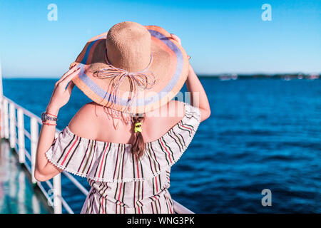 Cruise ship vacation woman enjoying travel vacation at sea. Free carefree happy girl looking at ocean and holding sunhat. Stock Photo