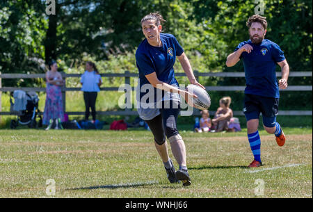 Amateur rugby touch player (female, 20-30 y) prepares to pass the ball as male teammate looks on Stock Photo