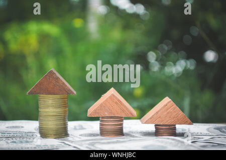 Close-up Of Model Houses Made With Stacked Coins And Wooden Cubes On Paper Currency
