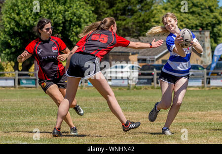 Amateur rugby touch player (female, 14-20 y) evades touch tackle from two female opponents Stock Photo