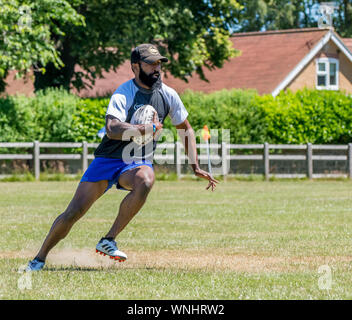Amateur rugby touch player (male, 40-50 y) runs forwards with rugby ball in hand Stock Photo