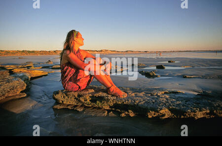 A young Australian woman enjoys a beautiful sunset at Cable Beach in Broome,  Western Australia. Stock Photo