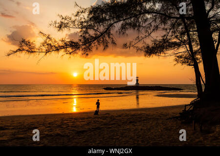 An orange sunset on a tropical beach with a small lighthouse (Khao Lak, Thailand) Stock Photo