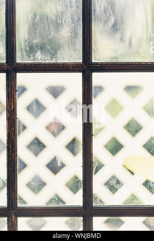 Wooden vintage door with dirty windows and white porch behind it. Stock Photo