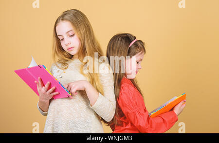 Friendship and sisterhood. students reading a book. School project. workbooks for writing. Back to school. small girls with note books. happy little children ready for lesson. Inspired to work hard. Stock Photo