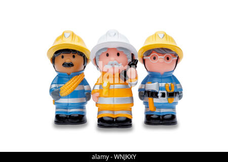 A line of 3 toy firefighters standing to attention, shot on a white background Stock Photo
