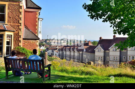 Two people sitting on park bench in Redland overlooking Bristol, UK Stock Photo