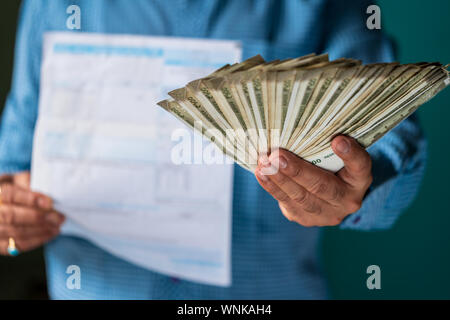 Indian male citizen paying his electricity, grocery, water, gas, DTH and other monthly bills and tax. Tax and bill payment concept with copyspace. Stock Photo