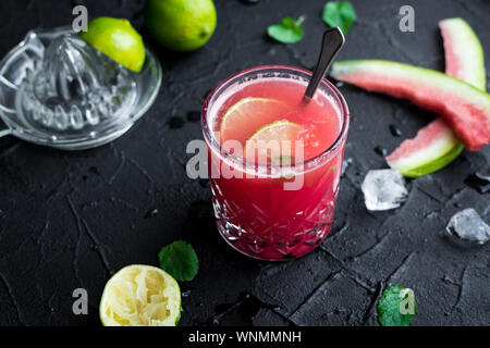 Watermelon drink in glasses with lime and mint on black background. Stock Photo