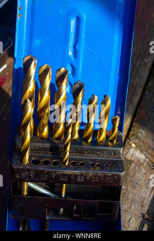 Set of golden drill bits on a wooden table seen close up Stock Photo