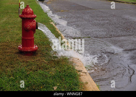 Open fire hydrant water flowing from open fire hydrant on street Stock Photo