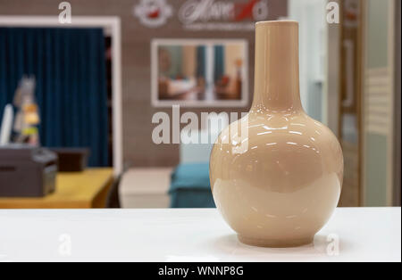 Beige ceramic vase of simple form on a white table. Stock Photo