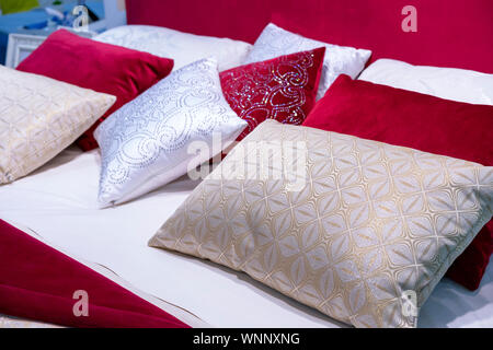 Decorative pillows from velvet and brocade on the bed in the bedroom. Stock Photo
