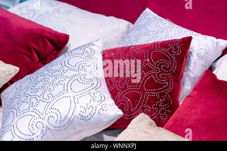 Decorative pillows from velvet and brocade on the bed in the bedroom. Stock Photo