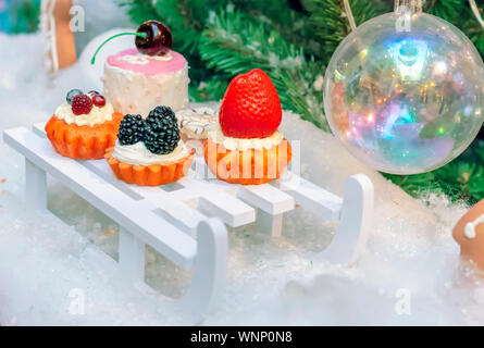 Decorations in the form of a variety of cakes on the background of the Christmas tree. Stock Photo