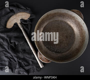empty crooked vintage aluminum stewpan and old knife on a black background with black gauze fabric, top view Stock Photo