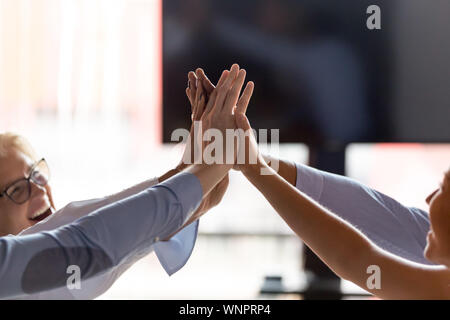 Close up of excited employees join hands for shared success Stock Photo