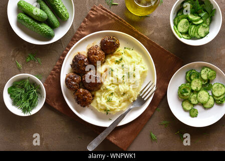 Minced meat cutlets with mashed potatoes and vegetable salad over brown background. Top view, flat lay Stock Photo