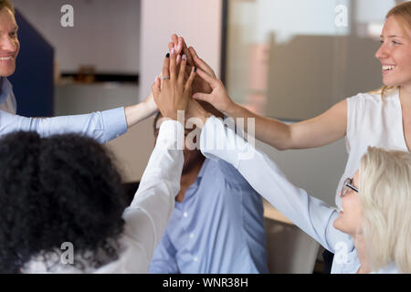 Close up of excited employees join hands showing unity Stock Photo