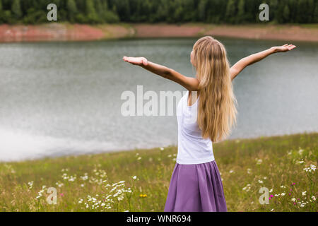 Woman with her arms outstretched enjoys spending her time in beautiful nature. Stock Photo