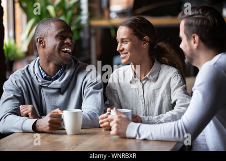 African American and Caucasian friends having fun together in coffeehouse Stock Photo