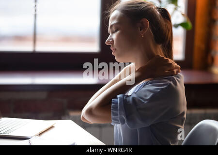 Tired woman feeling pain in neck pain after sedentary work Stock Photo