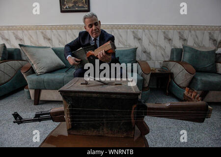 Baghdad, Iraq. 06th Sep, 2019. Iraqi teacher and musician Majed Abdennour plays music behind a musical instrument made from a Kalashnikov assault rifle and an ammunition box. Abdennour had the Kalashnikov at home between 2006 and 2008 to protect his family during the sectarian violence between the militias and extremists of the Iraqi Sunnis and Shiites factions. After more than 10 years of abandoning his weapon, Abdennour decided to bring it to a metalworker to transform it into a musical instrument that performs as a lute. Credit: Ameer Al Mohammedaw/dpa/Alamy Live News Stock Photo