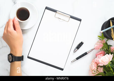 Pink work desk with female hand writes notes in notebook at