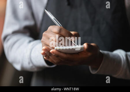 Close up African American waiter hands with notebook, taking customer order Stock Photo