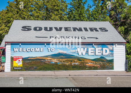 A large building in Weed California with a painted mural of the local landscape that serves as a welcoming sign for the town. Stock Photo