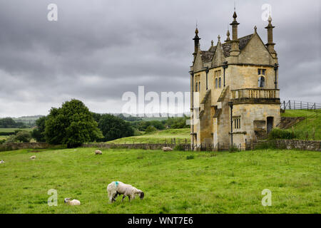 Sheep grazing in field at 17th Century East Banqueting Hall beside St James' church under cloudy sky in Chipping Campden England Stock Photo