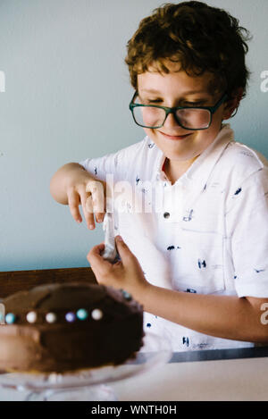 Tween decorating his birthday cake with candy pieces. Stock Photo