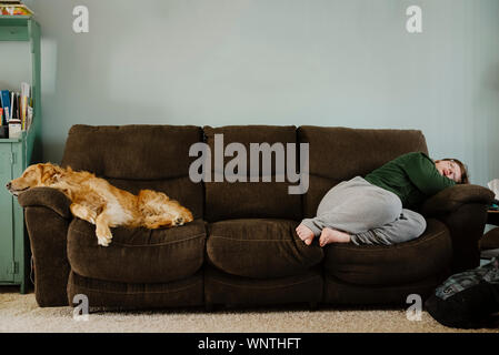 Golden Retriever and teen girl laying down on the couch indoors. Stock Photo