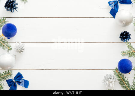 Christmas frame with blue balls, fir tree branches, gift boxes, ornaments on wooden white background. New year holiday festive banner mockup. Christma Stock Photo