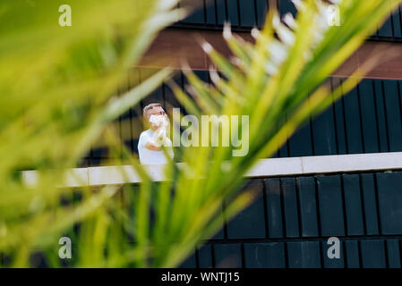 Mature bearded man using a mobile phone while walking on a sunny day Stock Photo