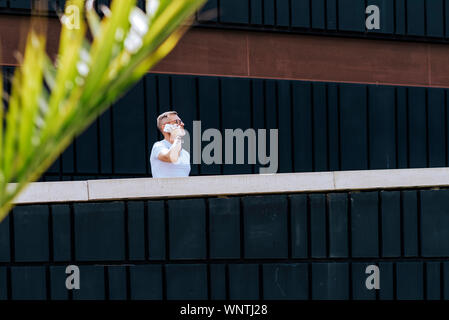 Mature bearded man using a mobile phone while walking on a sunny day Stock Photo