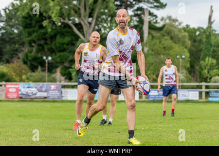 Amateur touch rugby player (male, 40-50 y) prepares to pass the ball to teammate Stock Photo