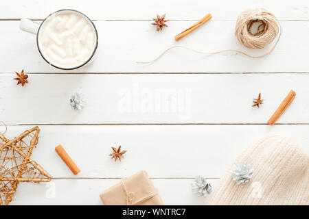 Christmas minimal composition. Flatlay cup of hot chocolate with marshmallow, cinnamon sticks, Xmas decorations, gift box wrapped kraft paper, knitted Stock Photo
