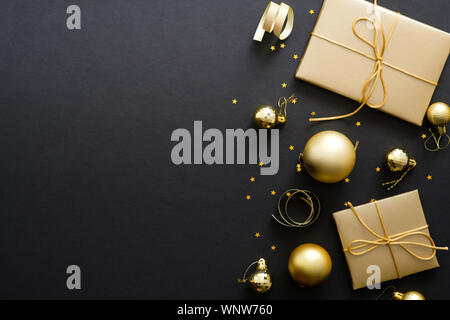 Elegant Christmas background with modern golden Christmas decorations, baubles, gift boxes, confetti stars on dark black backdrop. Flat lay design, to Stock Photo