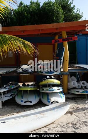 Wind surfboards stacked on top of each other in the sand