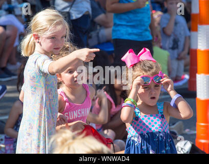MATTHEWS, NC (USA) - August 31, 2019: Enthusiastic young spectators watch the Labor Day parade held at the annual 'Matthews Alive' community festival. Stock Photo