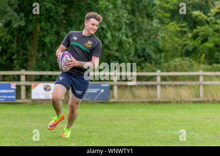 Amateur touch rugby player (male 20 y) running with rugby ball in hands, smiling Stock Photo
