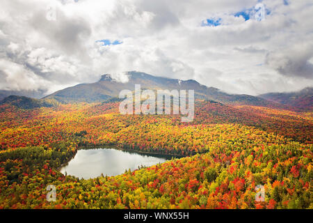Colorful overlooks views of endless forest in full fall colors with ponds throughout the states of New York, New Hampshire, Vermont, New England. Stock Photo