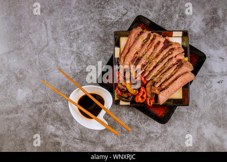 Chinese style sliced roast beef steak fried mushrooms sesame seeds, soy sauce with chopsticks Stock Photo